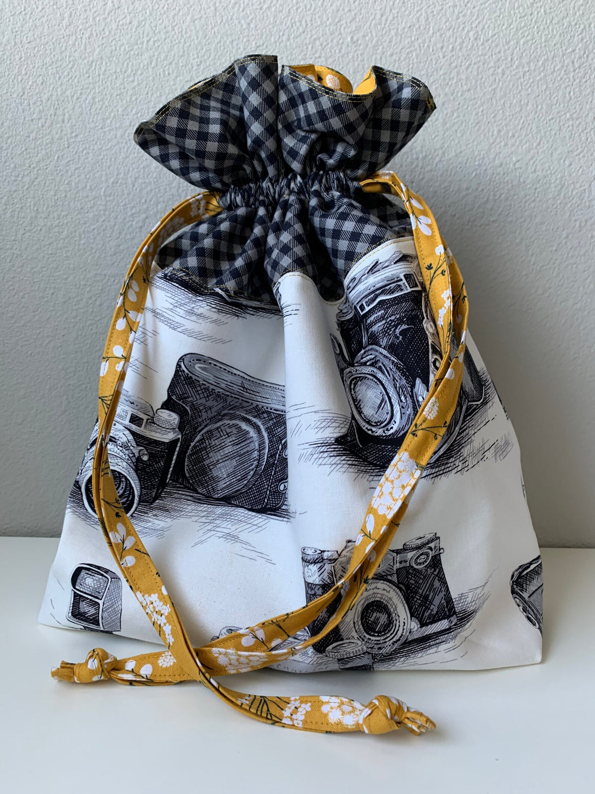 Camera print drawstring project bag tied closed with mustard floral fabric ties