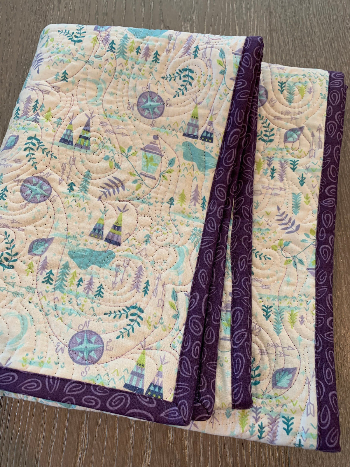 Folded handmade Bohemian Neverland adventure baby quilt with purple paisley binding