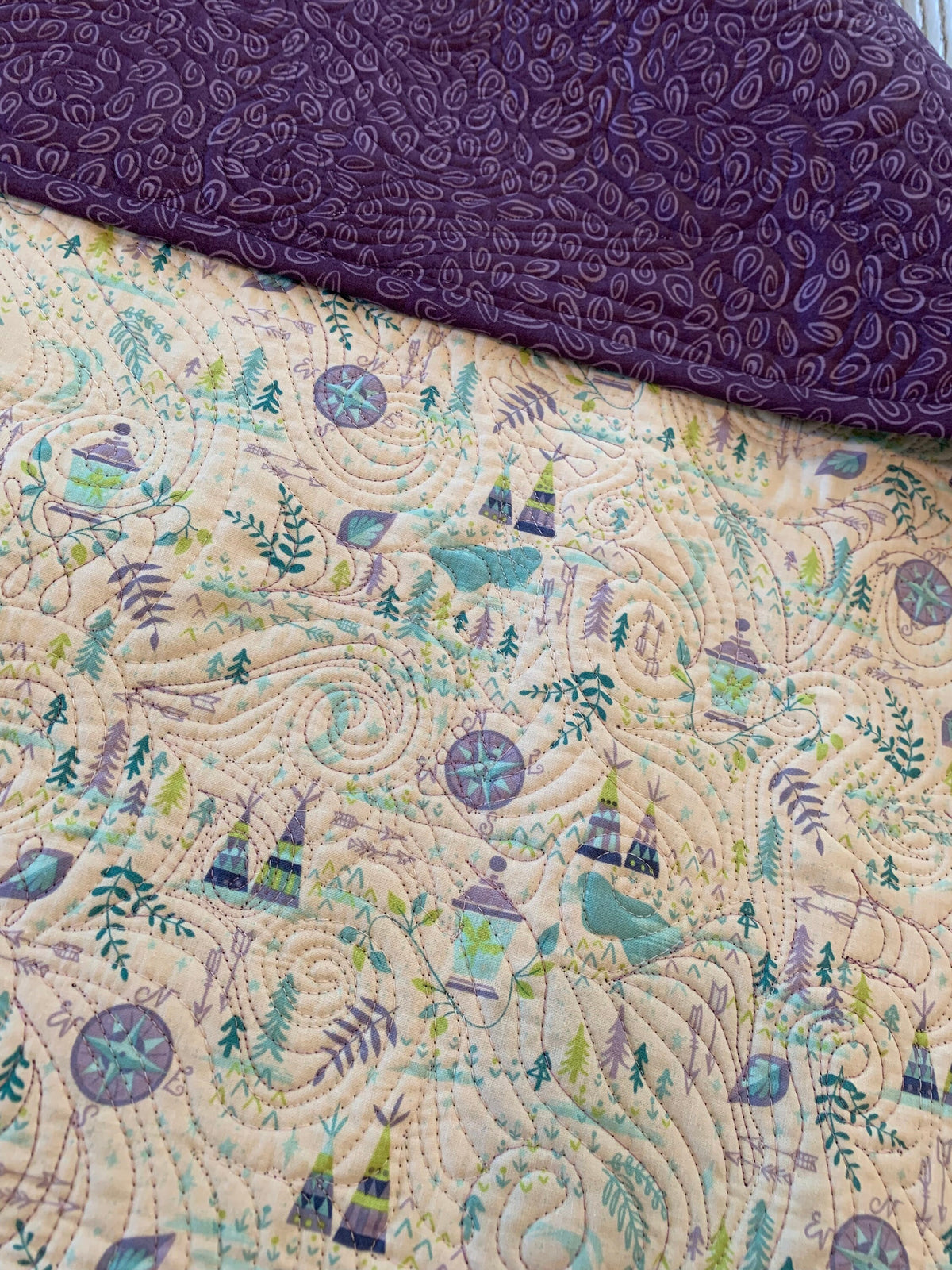 Close-up of cotton adventure print and purple paisley backing on handmade baby quilt