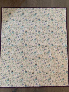 Full view of handmade whole-cloth adventure baby quilt with purple binding