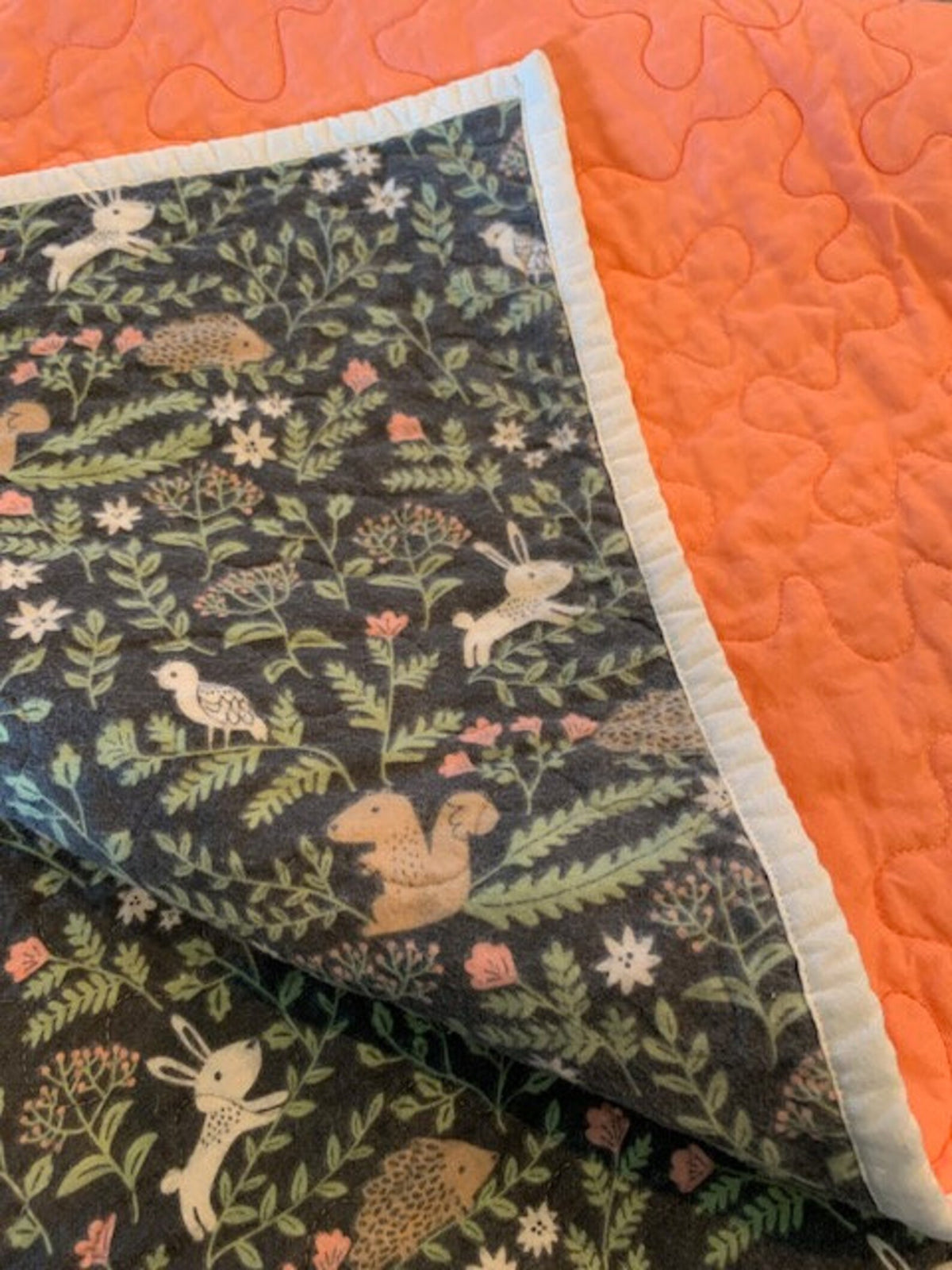 Close-up of light-colored binding on woodland flannel baby quilt