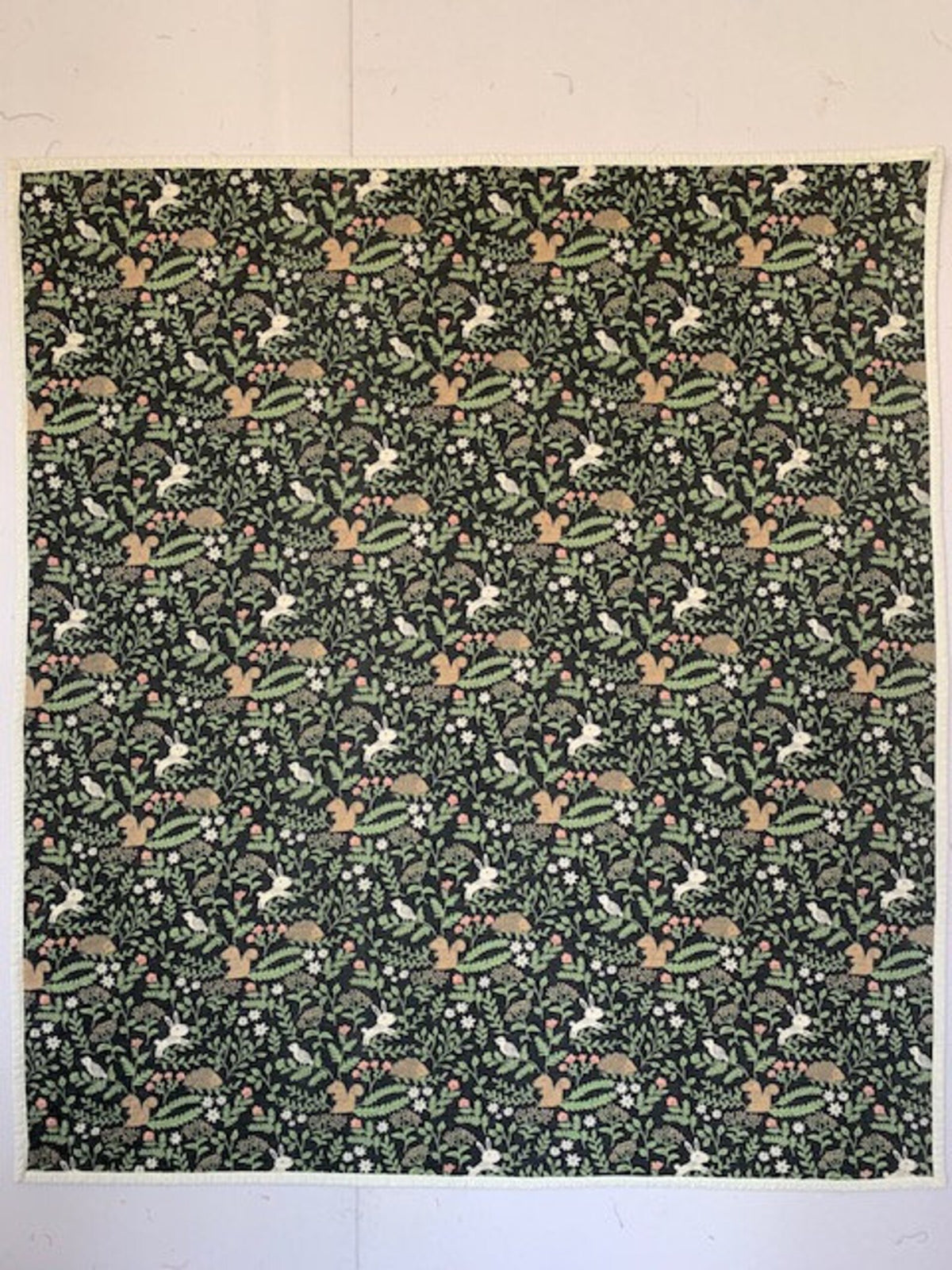 Full front of handmade forest baby quilt with rabbits, squirrels, hedgehogs, birds, and flowers.